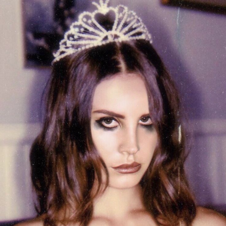 a young woman wearing a tiara and makeup looks at the camera while posing for a photo