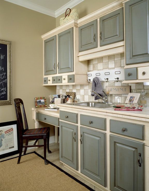 a kitchen with gray cabinets and a wooden chair next to the sink in front of it