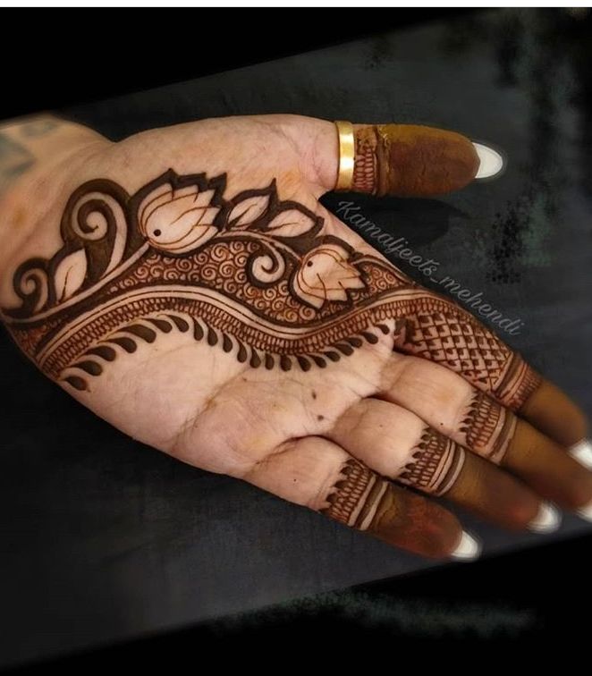 a hand with henna tattoos on it and some flowers in the middle of it