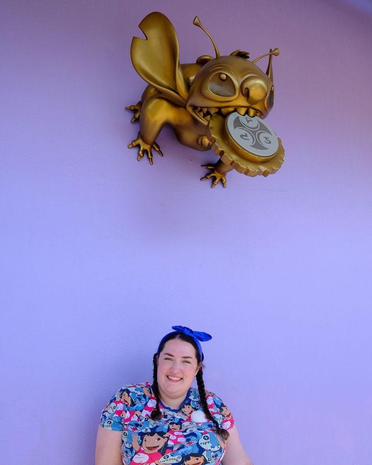 a woman sitting in front of a purple wall with a gold dragon clock on it