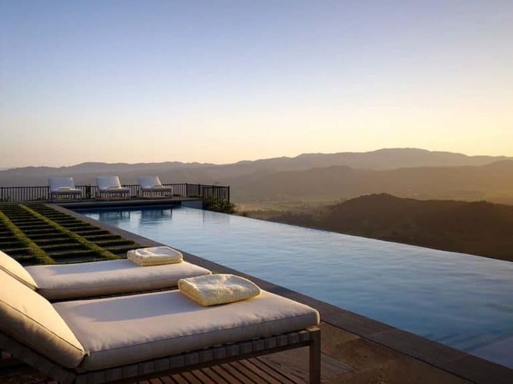 an outdoor pool with chaise lounges and mountains in the background