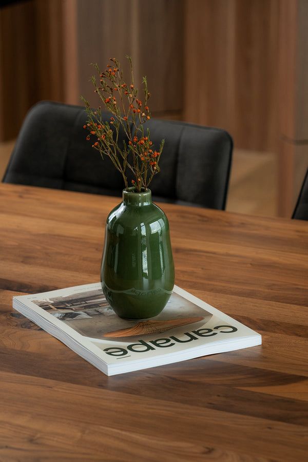 a green vase sitting on top of a wooden table