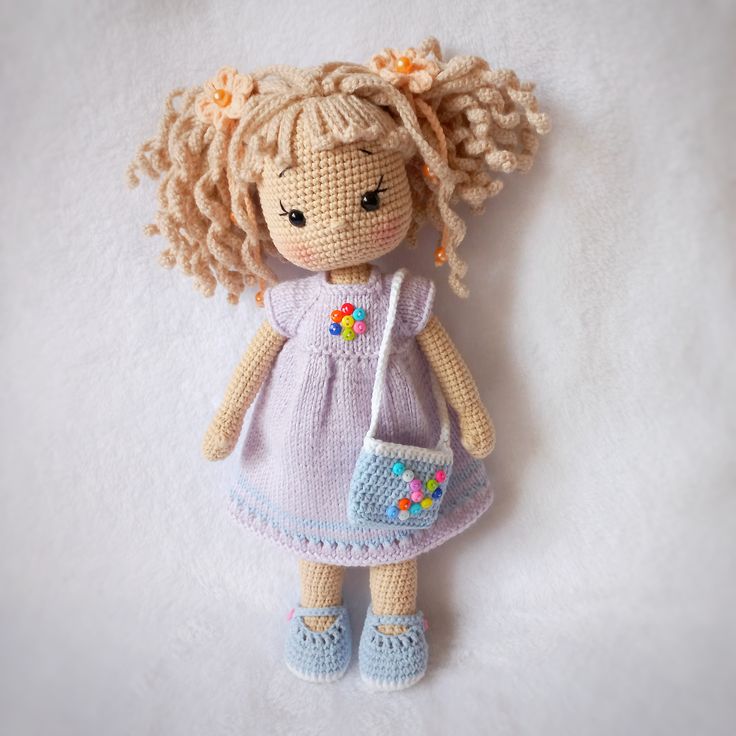 a crocheted doll with blonde hair holding a purse on a white background,