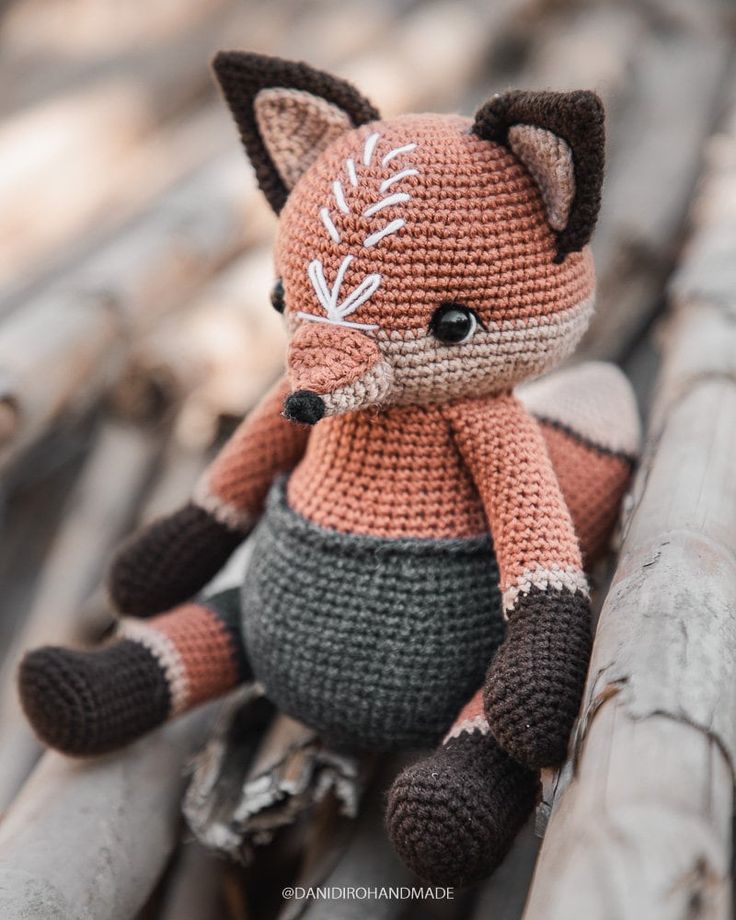 a crocheted stuffed animal sitting on top of a piece of wood