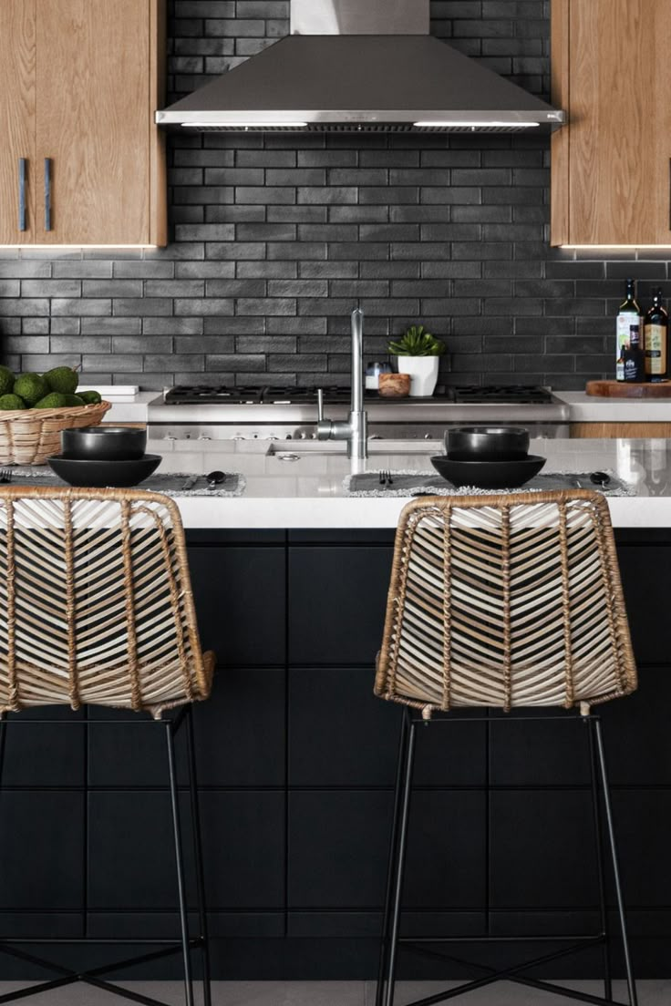 two wicker chairs sit in front of a kitchen island with black tile backsplash