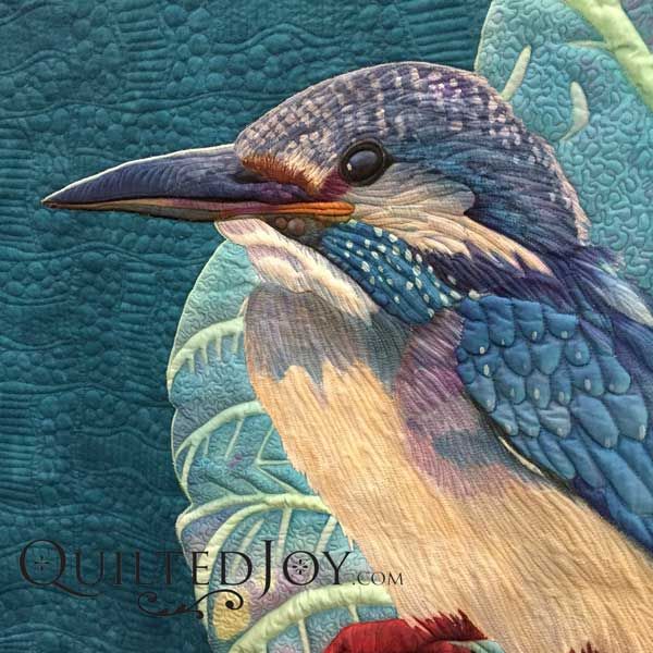 a painting of a bird sitting on top of a blue and yellow quilted piece