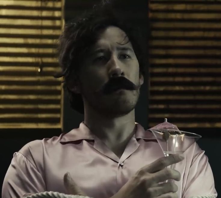 a man with a moustache on his face holding a wine glass in front of him