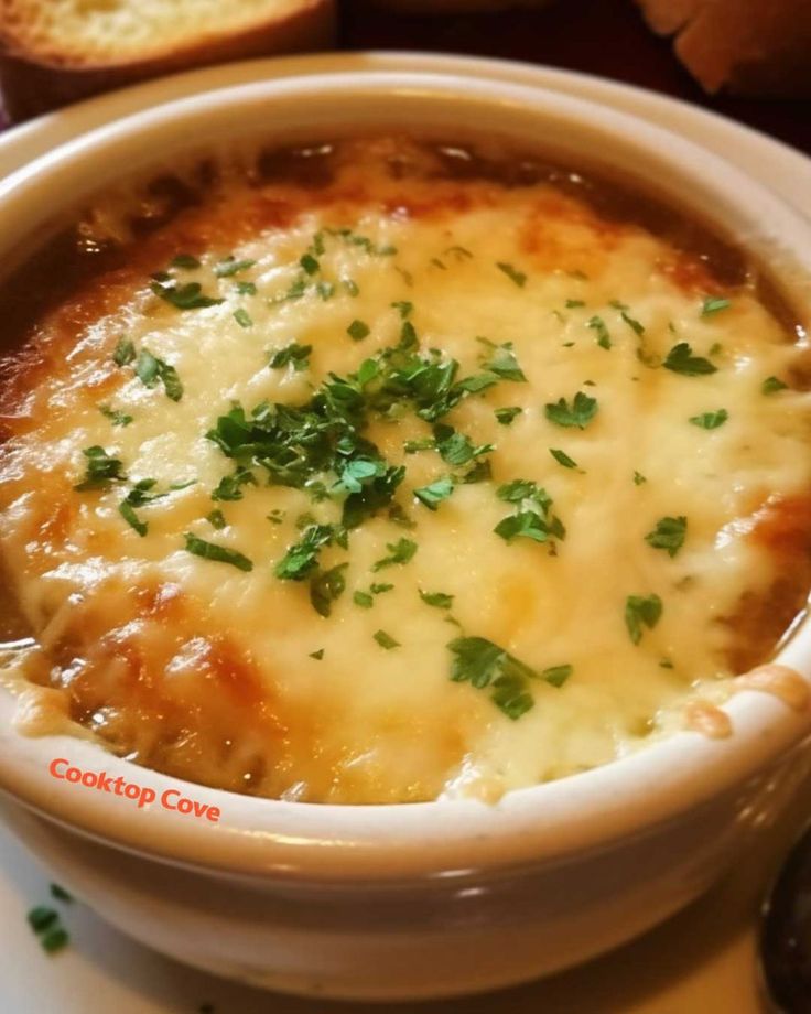 a white bowl filled with soup and bread on top of a table next to a plate