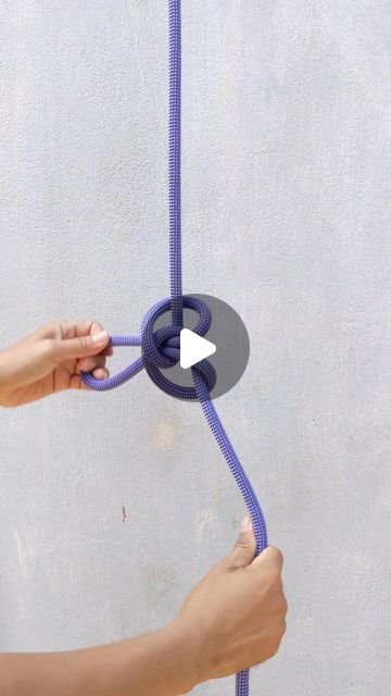 a person is holding a purple rope with an arrow on it and pulling the cord