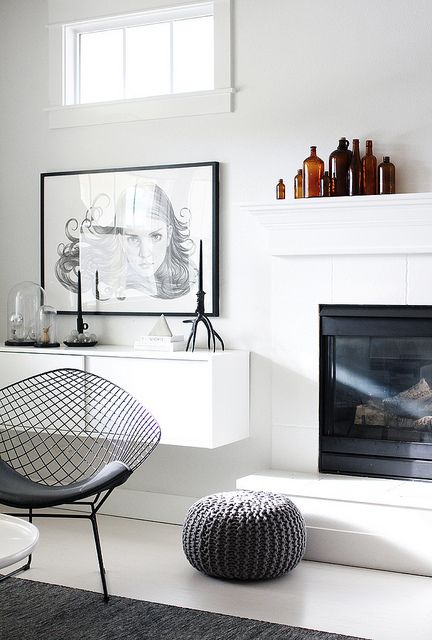 a white living room with a fireplace and chair next to the fire place in front of it