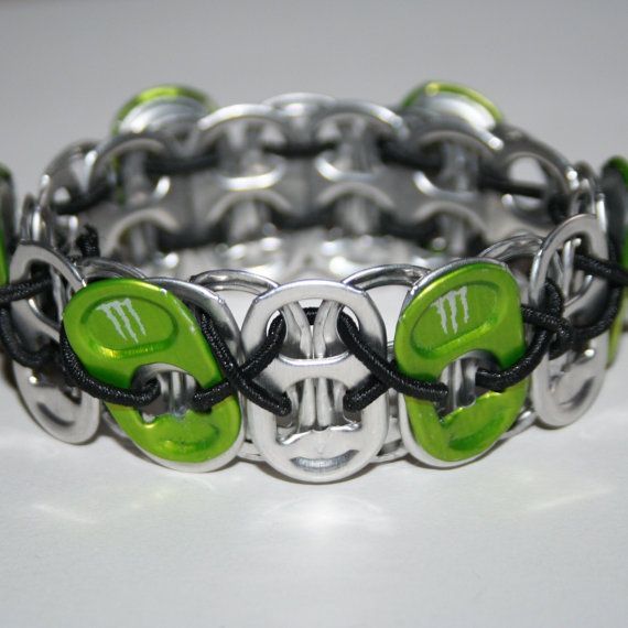 a bracelet with green and black beads is shown on a white surface, it looks like an interlocked chain