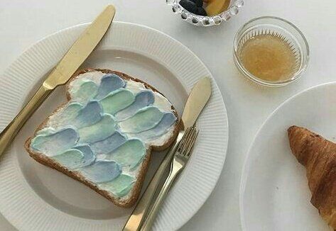 there is a piece of bread with blue icing on it next to a croissant