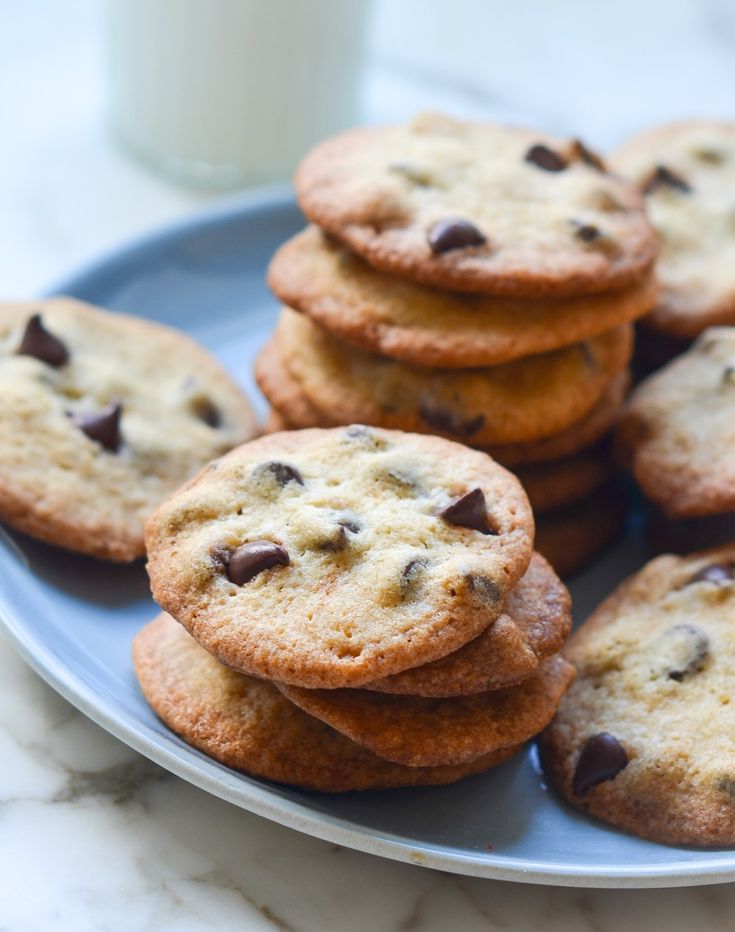 chocolate chip cookies on a blue plate with a glass of milk in the background,