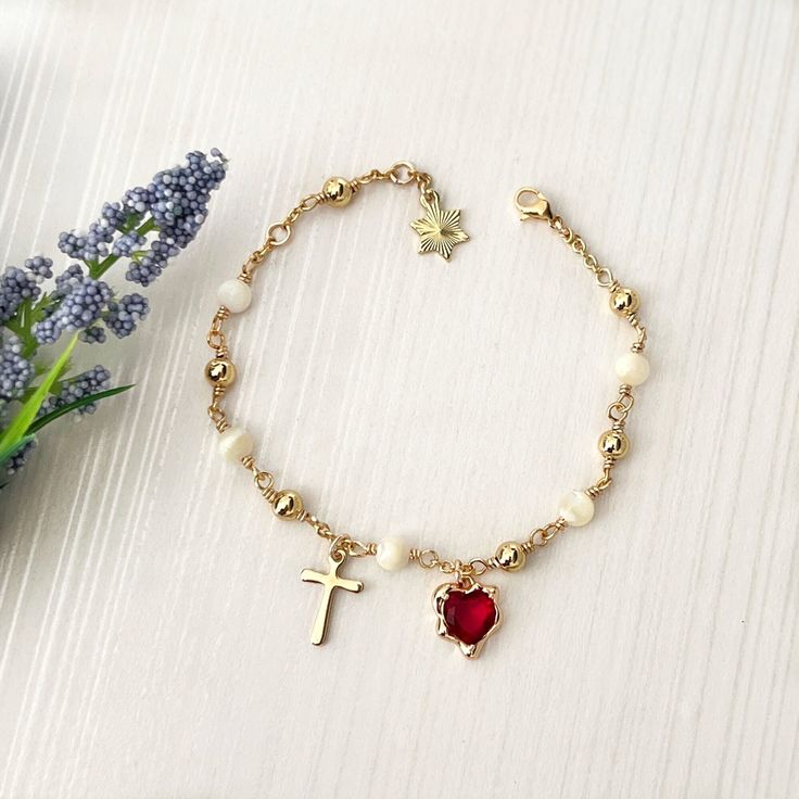 Our Sacred Heart rosary bracelet is handmade with Mother of Pearl gemstones, 18k gold-plated red cubic zirconia hearts, and 18k gold-plated beads. The Mother of Pearl gemstones symbolize purity and wisdom, while the red cubic zirconia heart represents the Sacred Heart of Jesus, radiating love and compassion. This rosary bracelet serves as a beautiful reminder of faith and grace. *  Adjustable from adult wrist 6 1/2" to 7 1/2". *  Total length: 8" (20cm). *  18k Gold-plated cubic zirconia heart. Gold Plated Bracelets For Valentine's Day Gift, Gold-plated Charm Bracelet For Valentine's Day, Gold-plated Rosary Bracelet For Gift, Gold Cubic Zirconia Beaded Bracelets As Gift, Ruby Bracelets As A Gift, Gold Crystal Bracelet For Valentine's Day Gift, Dainty Yellow Gold Rosary Bracelet As Gift, Gold Heart-shaped Crystal Bracelet Gift, Spiritual Rose Gold Rosary Bracelet Gift