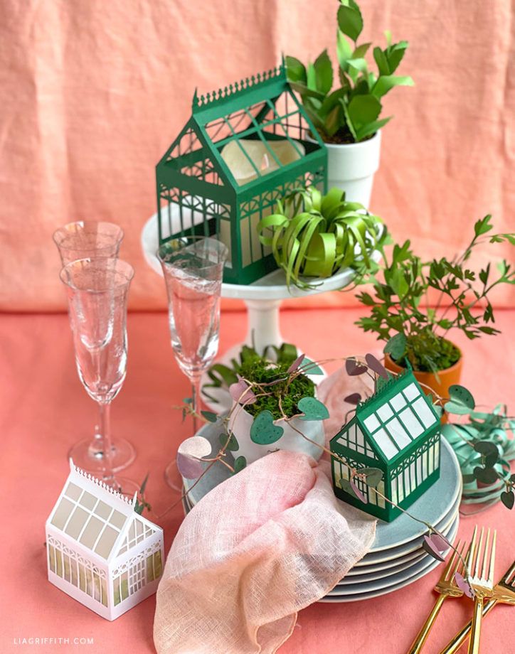 a table topped with plates and cups filled with plants on top of each other next to utensils