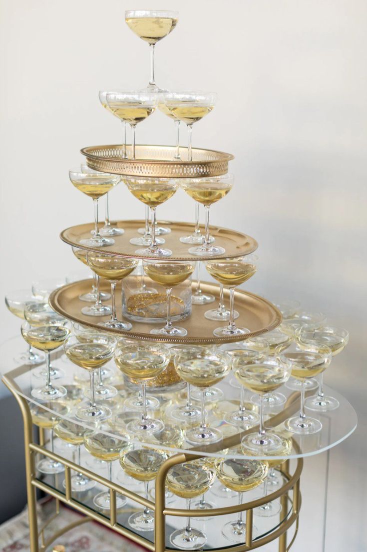 there is a gold tray with wine glasses on it that are stacked up and ready to be filled