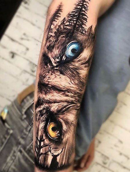 a person with a tattoo on their arm has an owl's face and blue eyes