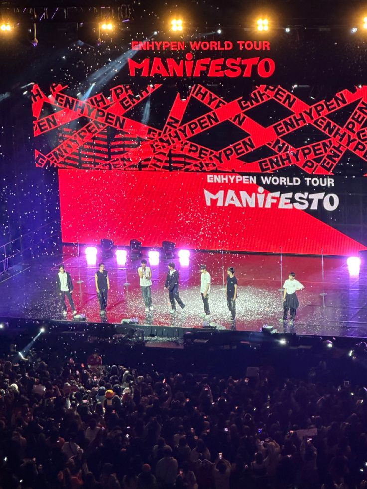 a group of men standing on top of a stage in front of a large crowd