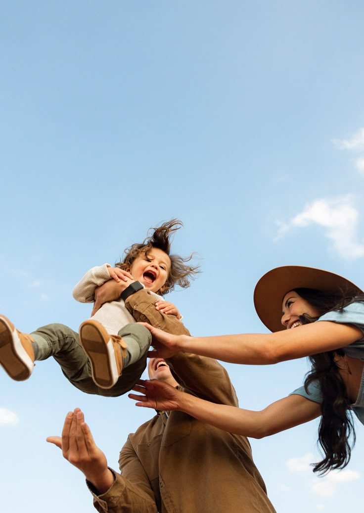 a woman holding a child in the air with her legs spread out and two other people behind her