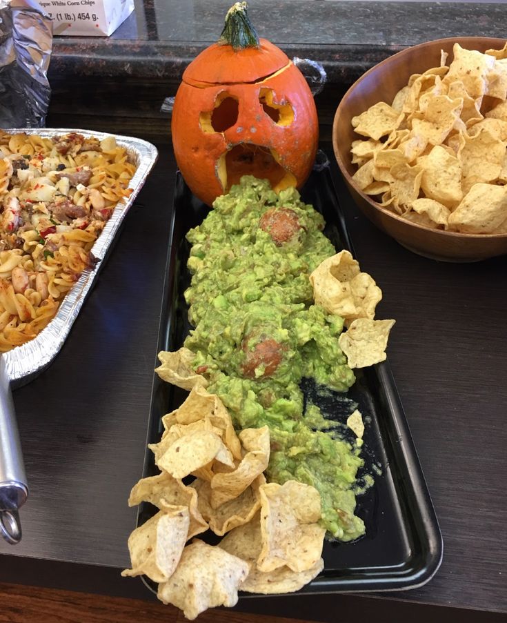 a tray with chips, guacamole and a jack - o'- lantern