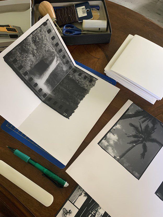 an open book on a table with some pictures and pens sitting next to it,