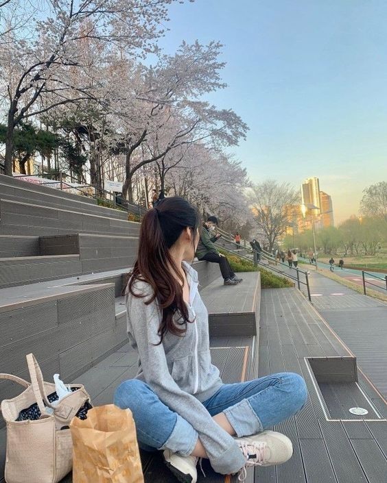 a woman sitting on top of a wooden bench