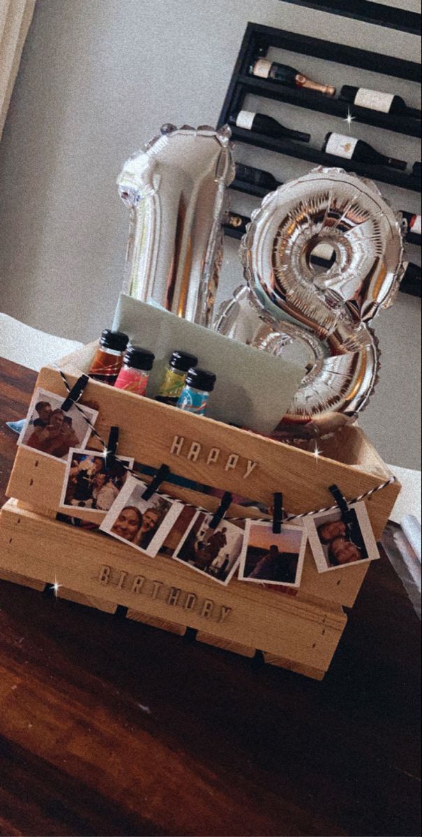 a wooden crate filled with personalized items sitting on top of a table next to balloons