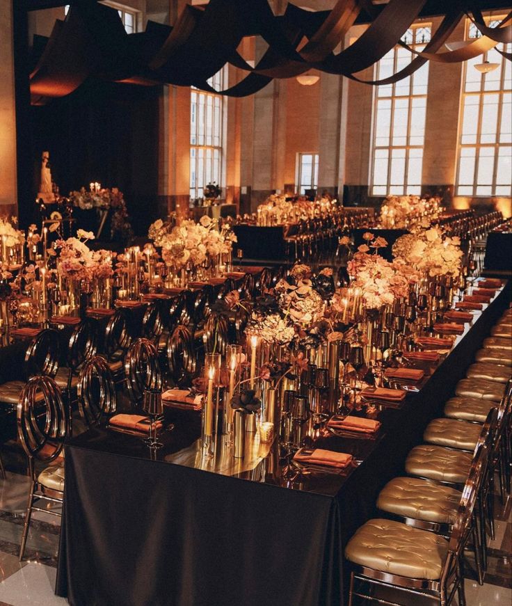 a long table is set up with gold and white flowers in vases on it