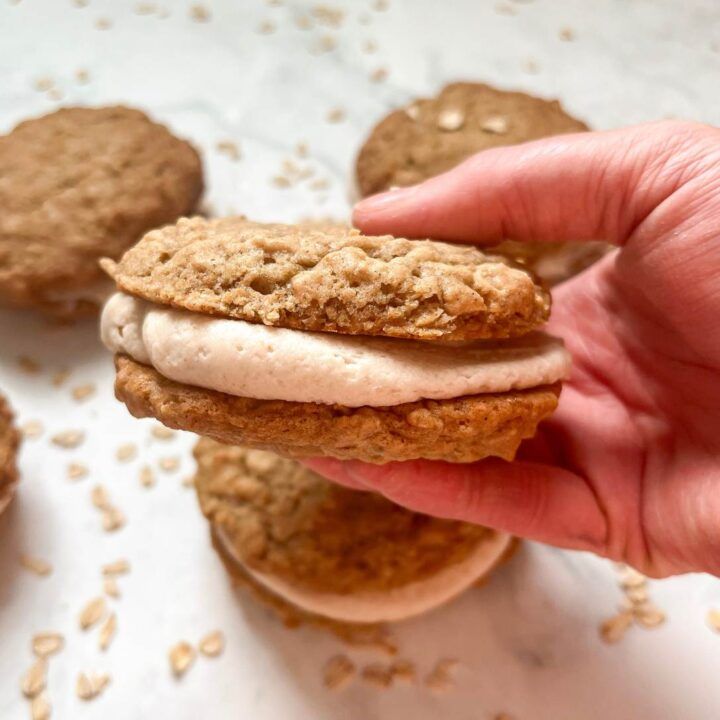 a hand holding an oatmeal cookie sandwich