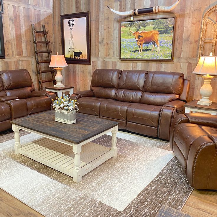 a living room with brown leather furniture and cow pictures on the wall behind the couches