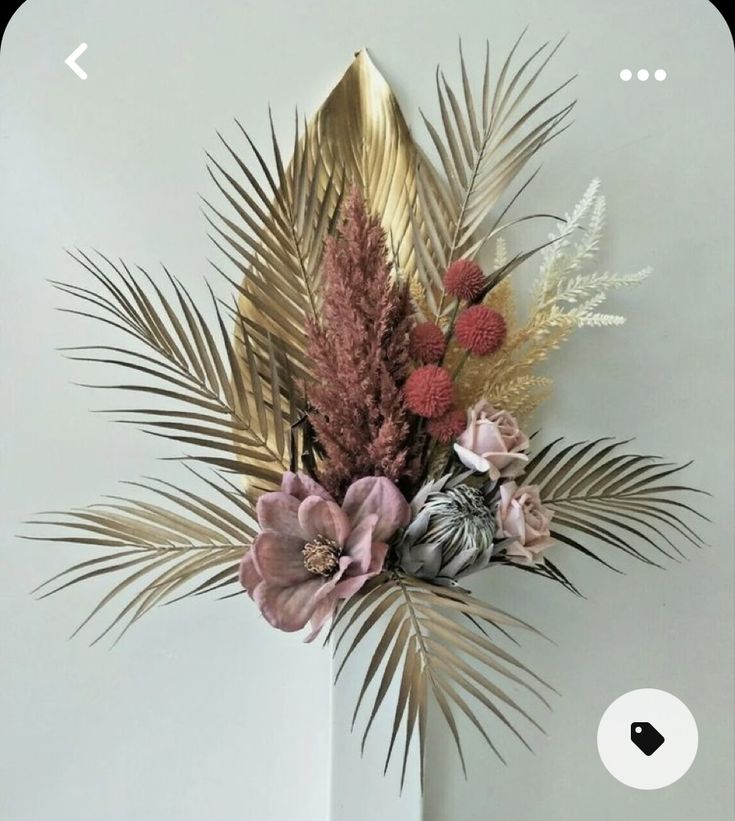 a white vase filled with lots of different types of flowers on top of a table