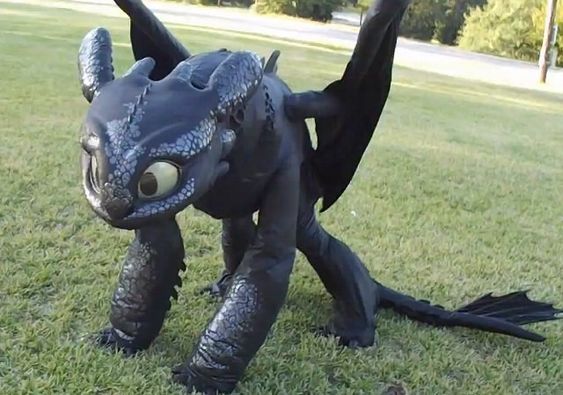 an inflatable dragon is sitting on the grass with it's eyes open