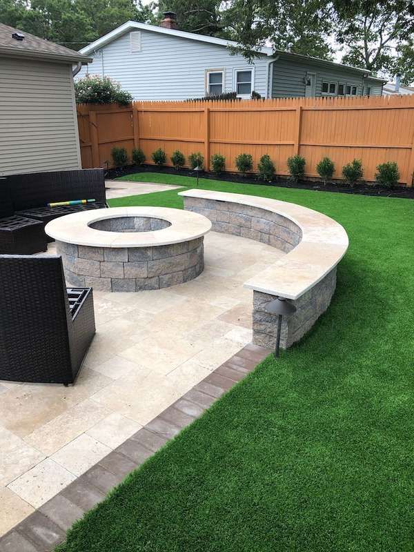 a backyard with artificial grass and an outdoor fire pit