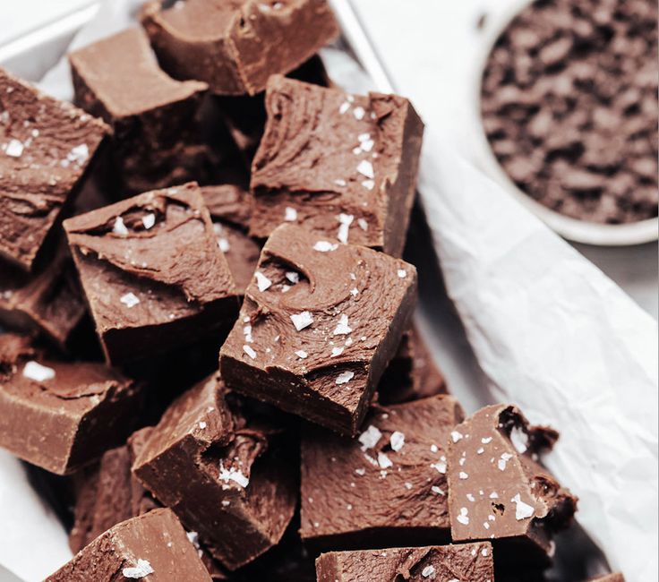 a pile of chocolate pieces sitting on top of a white plate next to a spoon