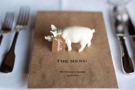 a small pig figurine sitting on top of a menu next to silverware