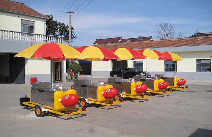 four yellow and red umbrellas sitting in the middle of a parking lot next to a building