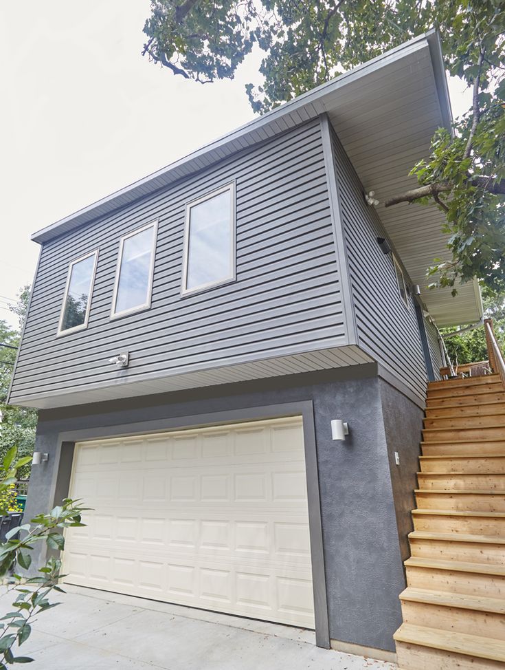 a two story house with stairs leading up to the front door and second story above it