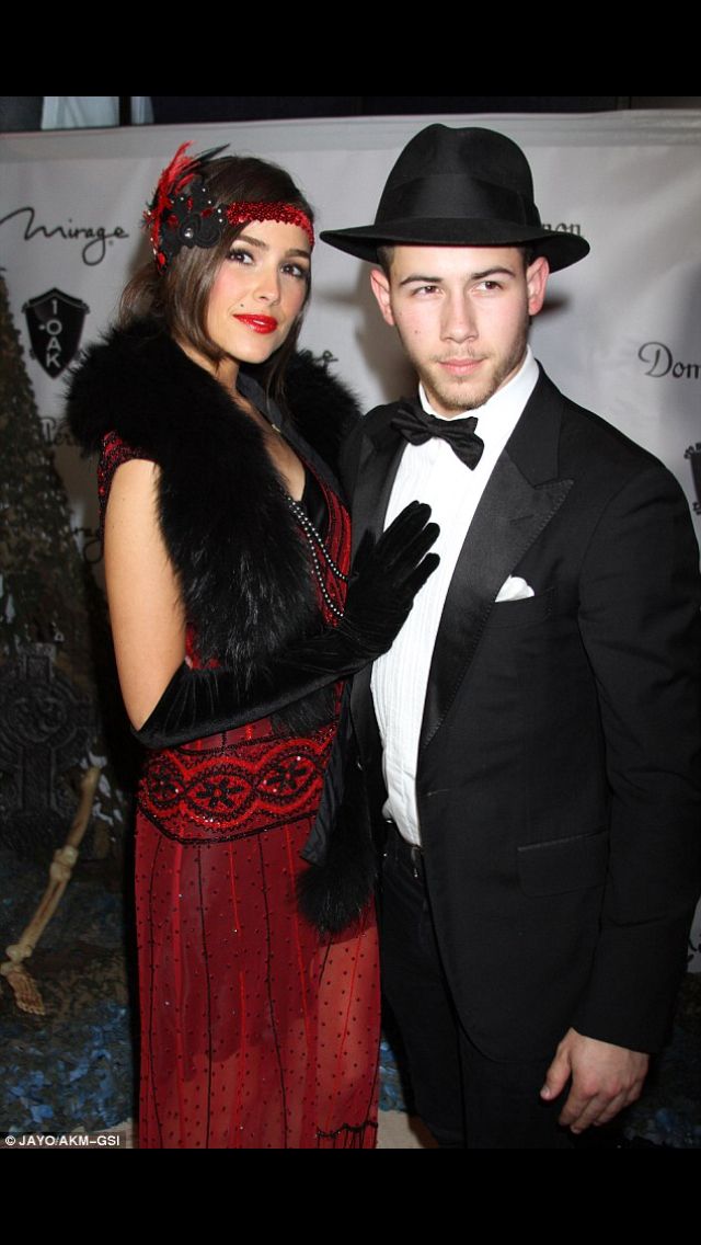 a man in a tuxedo standing next to a woman wearing a red dress