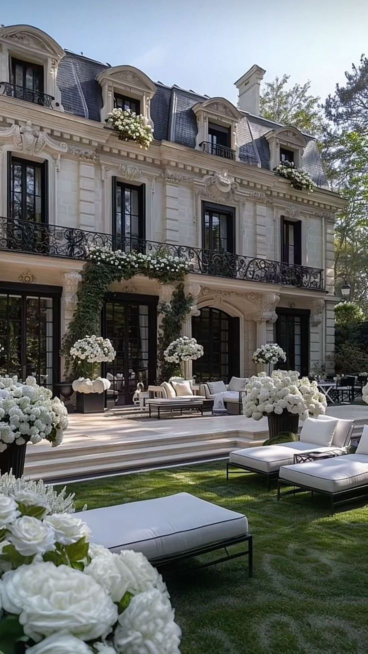 a large building with white flowers in front of it and some couches on the grass