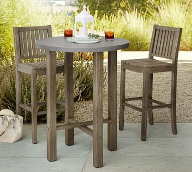 a table and two chairs sitting on top of a cement ground next to bushes with flowers in the background