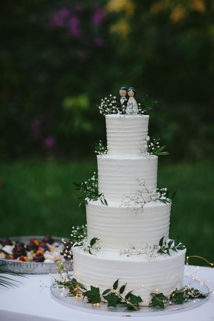 a wedding cake sitting on top of a table next to a plate with flowers and greenery