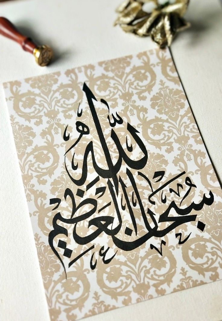 an arabic calligraphy is displayed on a piece of paper with a pen next to it