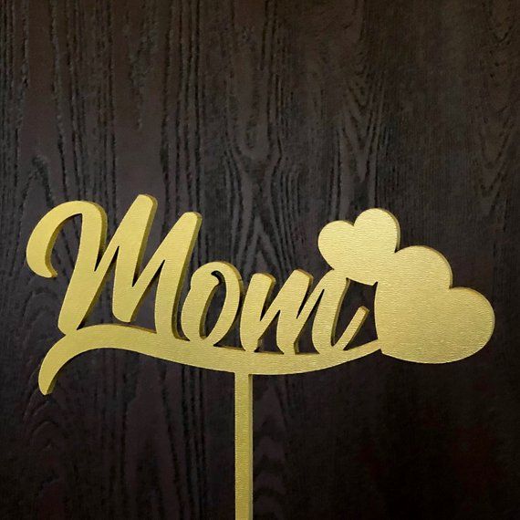 a cake topper with the word mom on it and two mickey mouse heads sticking out of it