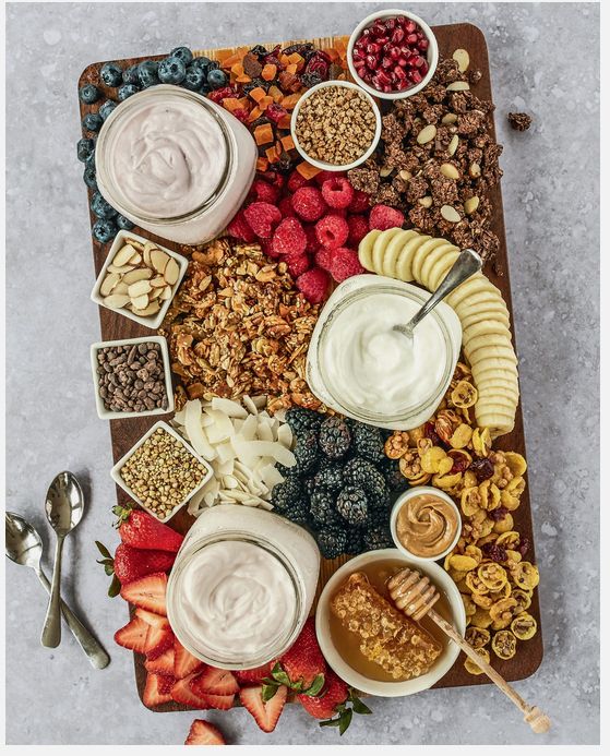 a wooden tray topped with different types of snacks and dips on top of each other