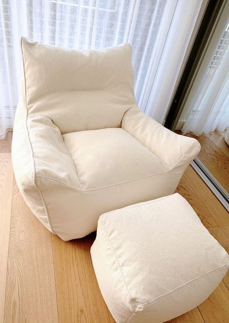 a white chair and ottoman in front of a window