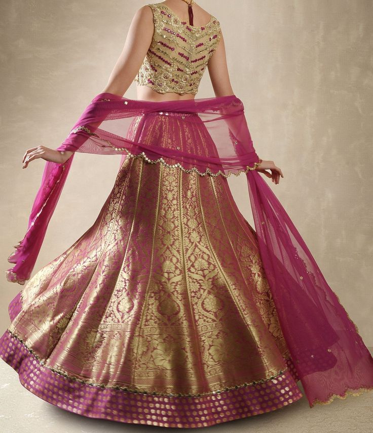 This exquisite Purple Pink Embroidered Banarasi Lehenga Set is crafted from luxurious Banarasi fabric, featuring rich kalidar purple pink lehenga adorned with a striking mirror-embellished belt and border that add a glimmer of sophistication to its traditional weave. Teamed with a classic mirror work blouse, intricately embellished with dori, mirrors, beads, and sequins, exuding an opulent charm. A lightweight tulle dupatta completes the look, delicately sprinkled with mirror buttis and finished Elegant Pink Banarasi Silk Lehenga, Elegant Pink Chanderi Choli, Elegant Pink Banarasi Silk Sharara, Gold Brocade Choli For Eid, Pink Brocade Traditional Wear For Festive Occasion, Festive Pink Brocade Traditional Wear, Elegant Pink Banarasi Silk Sets, Gold Anarkali Choli In Brocade, Anarkali Gold Brocade Choli