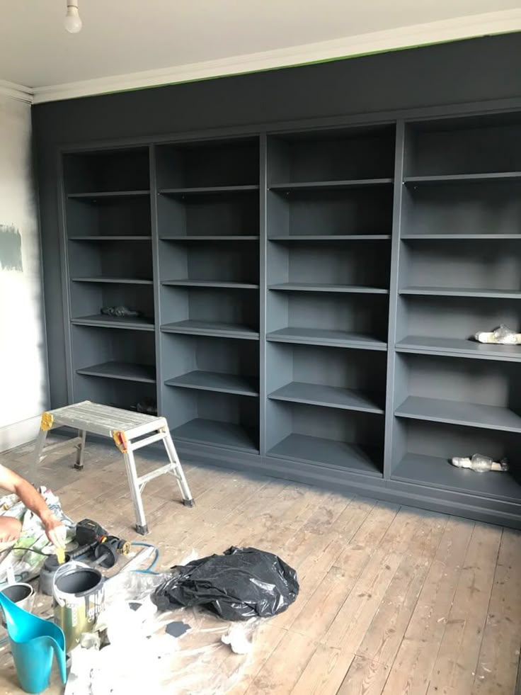 an empty room with several shelves and a ladder in the middle, all painted gray