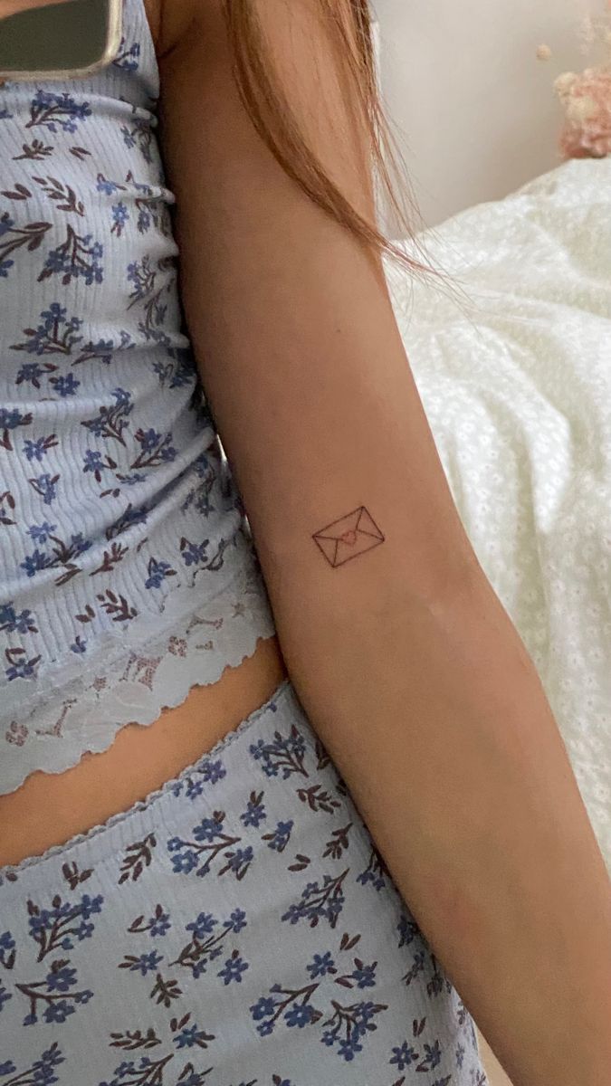 a woman's arm with a small envelope tattoo on the left side of her right arm