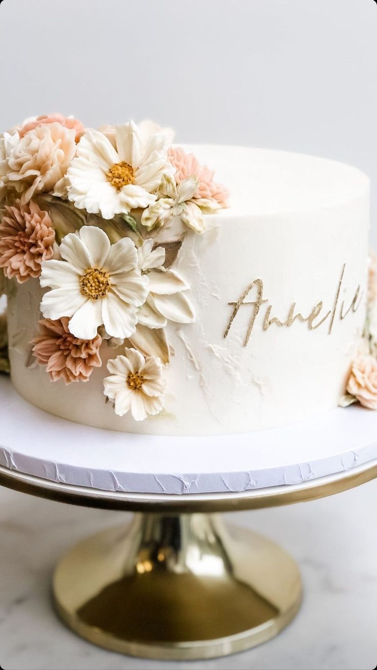 there is a white cake with flowers on the top and writing on the side that says angel