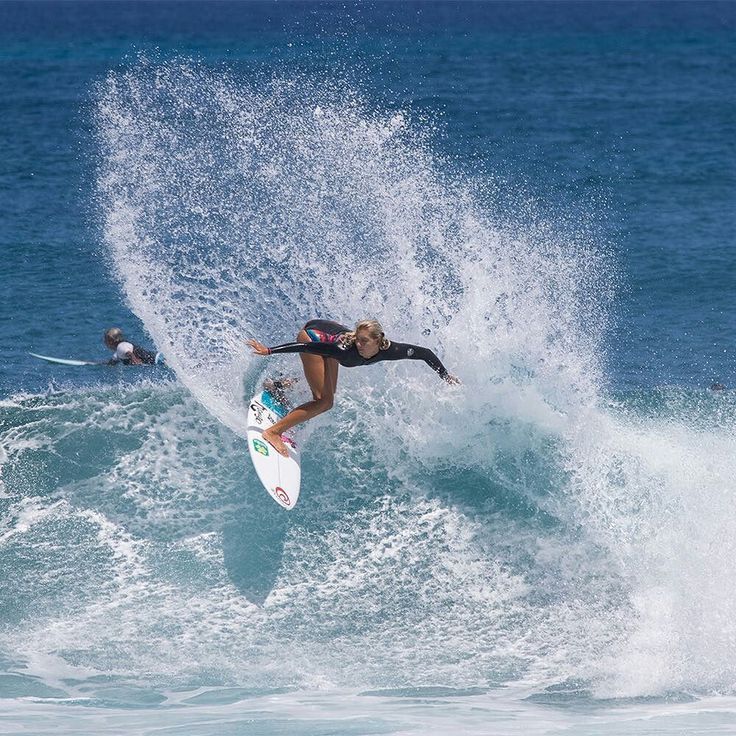 a woman riding a wave on top of a surfboard